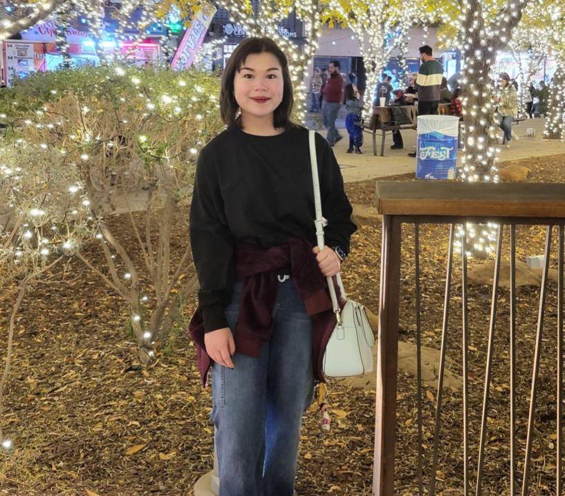 Girl standing under trees decorated with lights